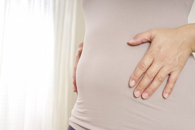 お腹を抱える妊婦の横姿