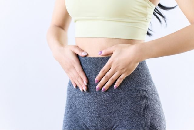 お腹に手を当てる女性の健康